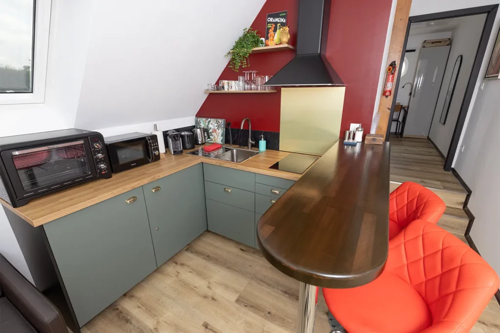 Studio 2 open-plan corridor with bar seating, kitchen and vintage film posters — Les Trois Cœurs Alsace