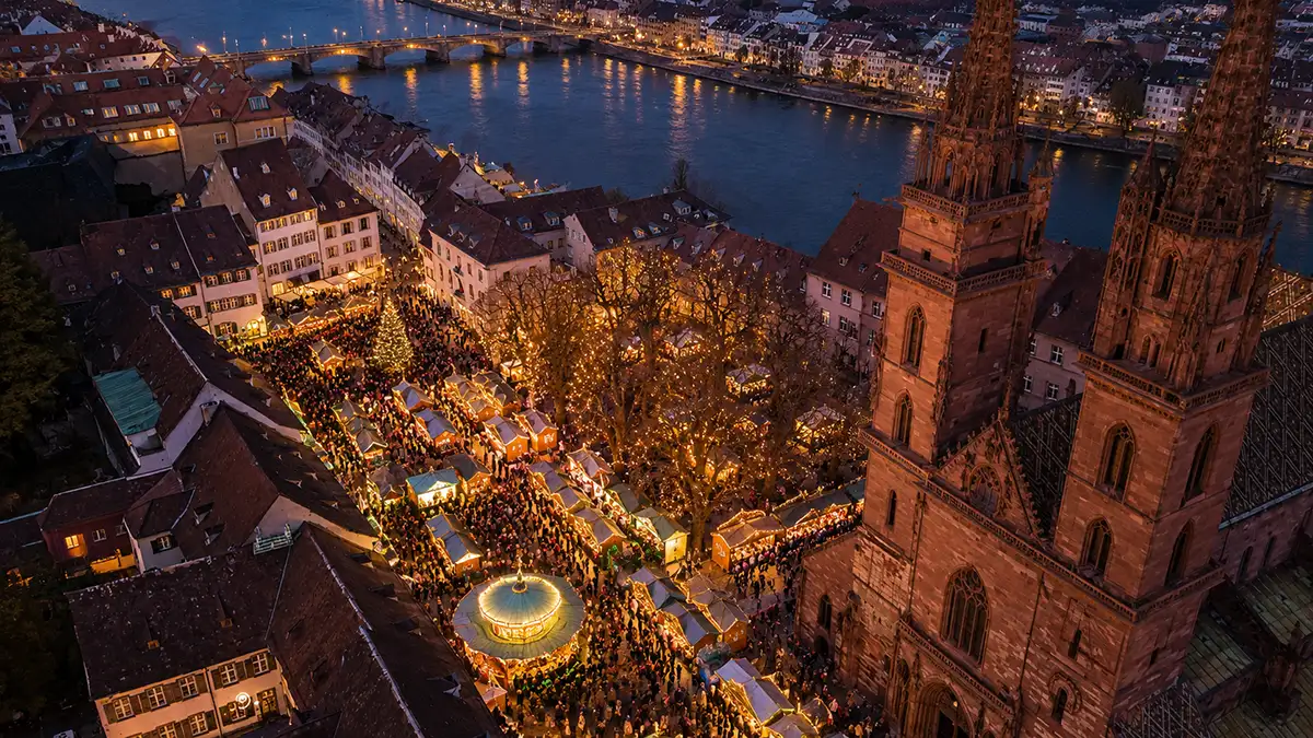Basel Christmas market at Münsterplatz — aerial view of illuminated stalls beside the Minster at dusk